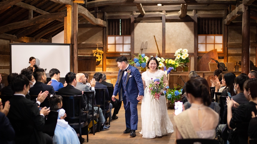 家族への手紙を読み上げる新婦と、その姿を温かく見守る新郎とゲスト。家族の絆が深まった感動的な挙式の一場面。