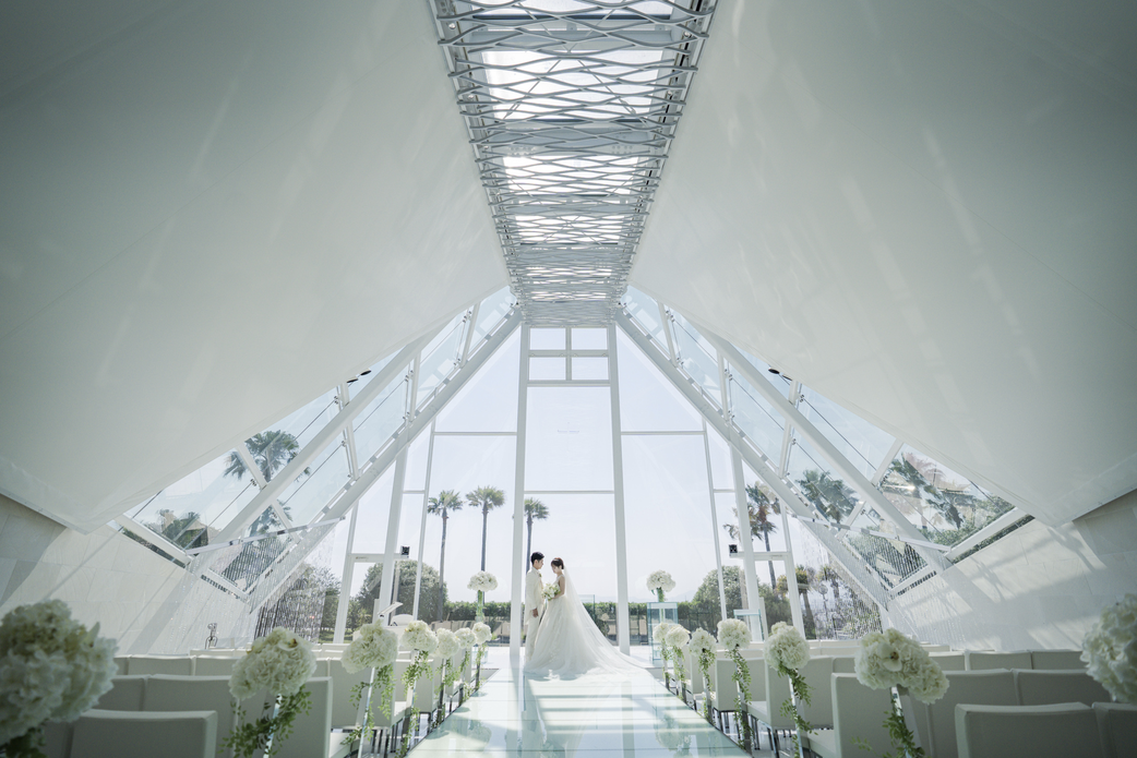 ラヴィマーナ神戸「海のチャペル」で、海と空を背景に高さのあるバージンロードに立つ新郎新婦